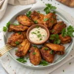 The Best Crispy Baked Chicken Wings – Easy & Flavorful! 8 A plate of crispy baked chicken wings garnished with parsley and served with dipping sauce.